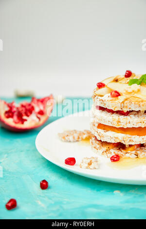 Vegan, dieta naturale organico torta di compleanno con riso croccante pane e frutta tropicale su sfondo blu. Facile cibo. Sana dessert a strati. Foto Stock