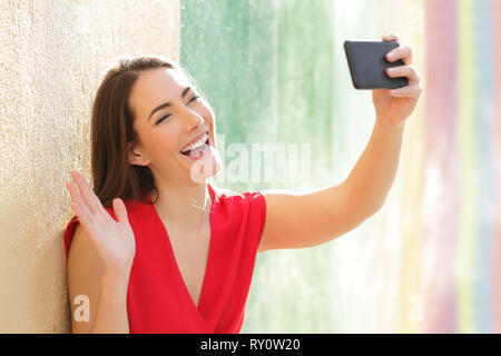 Felice moda donna prendendo selfies con smart phone in un colorato street Foto Stock