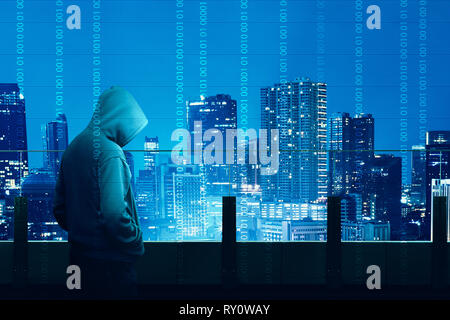 Vista posteriore di hacker in felpa con cappuccio nero permanente sulla costruzione terrazza guardando paesaggi urbani di notte con binario digitale sullo sfondo del codice Foto Stock