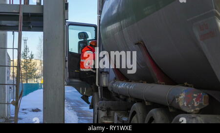 Un uomo in uniforme di andare all'interno del sedile dirvers del grosso camion Foto Stock