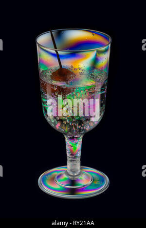 Interessanti modelli di accentazione in plastica vetro vino visto con red cherry cocktail sul bastone di gin e Bevanda tonica dando uno strano aspetto Foto Stock
