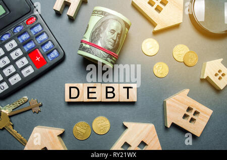 Case di legno, calcolatrice, chiavi, monete e blocchi con la parola debito. Il concetto di debito per alloggiamento. Ipoteca immobiliare. Prestiti concetto di proprietà. Foto Stock