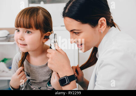 Sorridente bambina avente orecchio esame con otoscopio Foto Stock