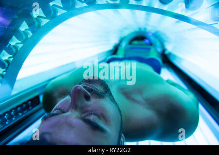 Giovane uomo muscolare presso il solarium nel Salone di bellezza Foto Stock