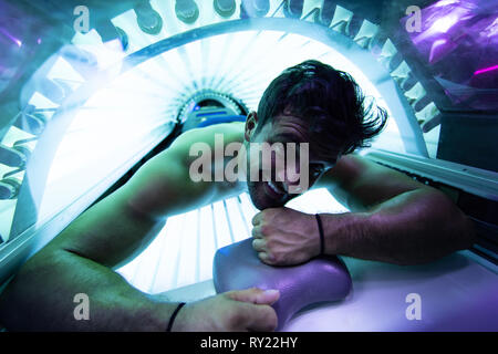 Giovane uomo muscolare presso il solarium nel Salone di bellezza Foto Stock