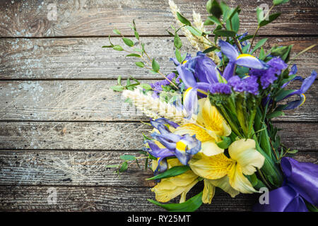 Bouquet di giallo e fiori viola, iris su sfondo di legno Foto Stock