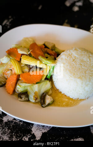 Gamberetti freschi fritti con babycorn, verze, carote e fungo poku servita con cotto a vapore di riso al gelsomino. Tradizionale a sud-est di cucina asiatica. Foto Stock