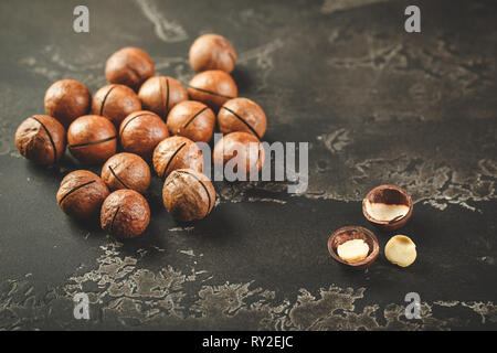 Noci di Macadamia in scuro su sfondo cemento vicino. Foto Stock