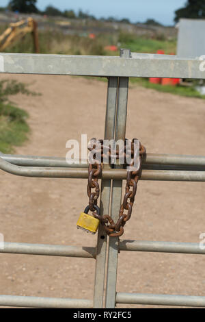 ​Metal cancelli, chiuso e protetto da una pesante catena di metallo e un lucchetto. La protezione della proprietà. Pratico e a vista, psicologico pensare sul wayward passanti. Foto Stock