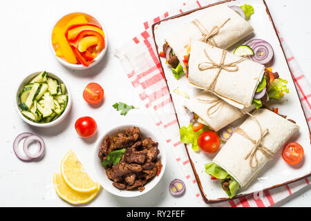 Burrito tortilla avvolge con manzo e verdure su bianco. Foto Stock