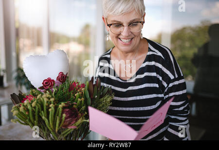 Felice Festa della mamma. Una donna matura, madre e nonna di lettura di un artigianale di giorno della madre card da bambini o nipoti Foto Stock