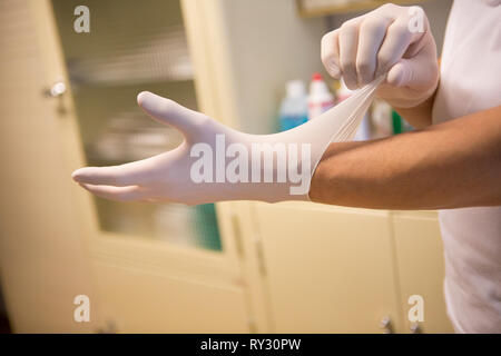 Guanti di protezione di lattice, essendo posto in un ambiente sanitario Foto Stock
