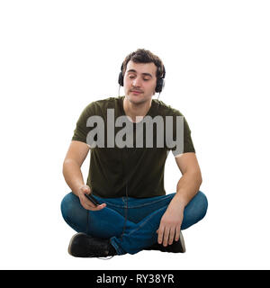 Giovane uomo bello rilassante seduta sul pavimento ascoltando musica in cuffia, tenendo il telefono in mano, la calma di fronte a occhi chiusi isolate su w Foto Stock