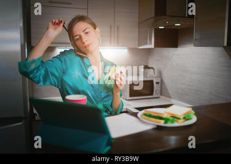 Donna di occupato di mangiare e di bere caffè, parlando al telefono, lavorando su un portatile allo stesso tempo. Imprenditrice di svolgere più compiti. Il Multitasking Foto Stock