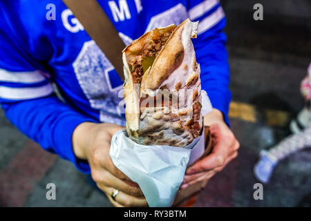 Avvolto libanese Manakish farcite con carne macinata tenendo nelle mani di una donna Foto Stock