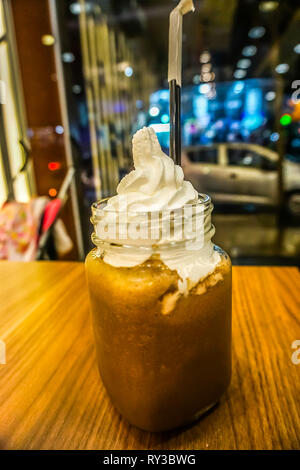 Cioccolato al latte shake in un vaso con una cannuccia conditi con panna montata Foto Stock