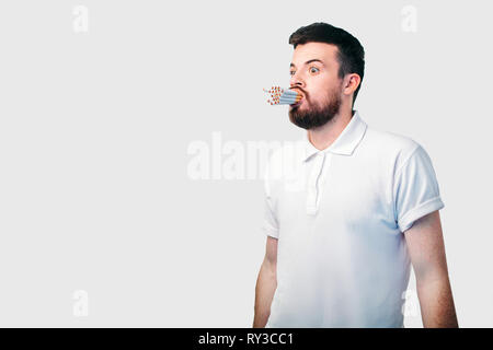 Concetto di fumare. Il barbuto dai capelli scuri guy detiene un sacco di sigarette nella sua bocca. Foto Stock