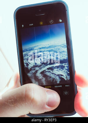 Stati Uniti d'America - 11 Maggio 2018: Closeup colpo di mano di raccolto utilizzando lo smartphone e iPhone per scattare delle foto dal piano della pittoresca nuvole con app Fotocamera Foto Stock