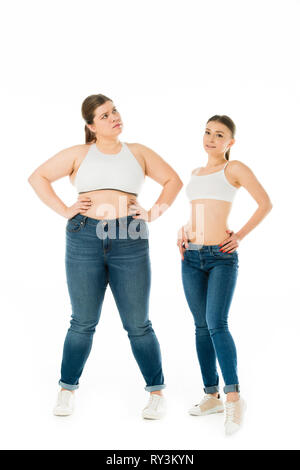 Allegro sottile e triste donne in sovrappeso in denim in posa con le mani sui fianchi insieme isolato su bianco, corpo il concetto di positività Foto Stock