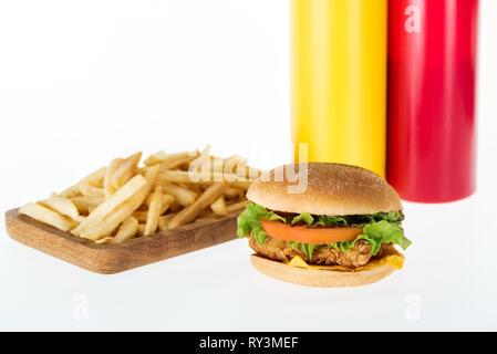 Gustoso pollo Burger vicino a patatine fritte e bottiglie isolato su bianco Foto Stock