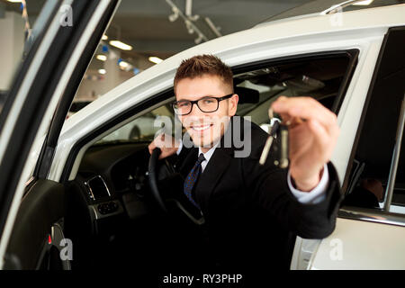 Venditore sorridente detiene le chiavi dell'auto in auto. Foto Stock