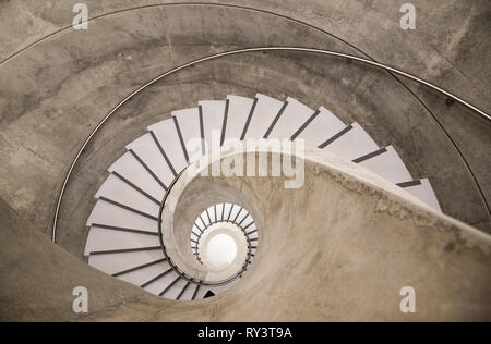 Vuoto a spirale interno moderno di cemento di scale che portano a un piano seminterrato Foto Stock