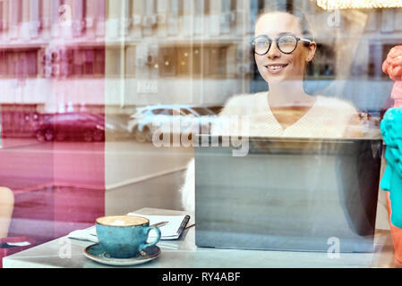 Attraente imprenditrice in ottica occhiali ridendo durante la conversazione di mobile con un amico tramite dispositivo smartphone.Positivo giovane donna parlando su t Foto Stock