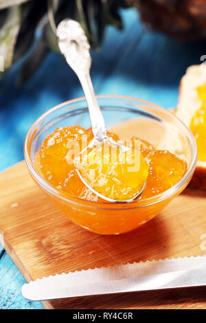 Confettura di ananas con ananas fresco e menta. marmellata sul cucchiaio e jar su sfondo blu Foto Stock