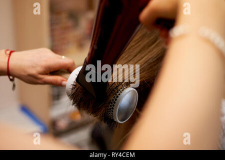 Lo styling dei capelli a spazzola tonda.essiccazione e posa su un pettine rotondo. Foto Stock