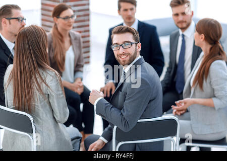 Giovane lavoratore seduto in un cerchio di colleghi Foto Stock