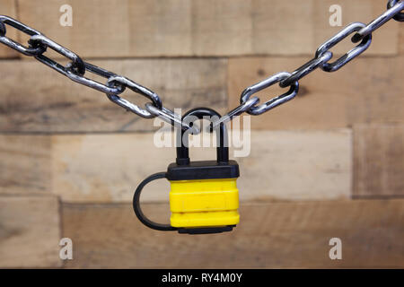Sicurezza serie concatenata lucchetto giallo su una tavola di legno sfondo modellato Foto Stock
