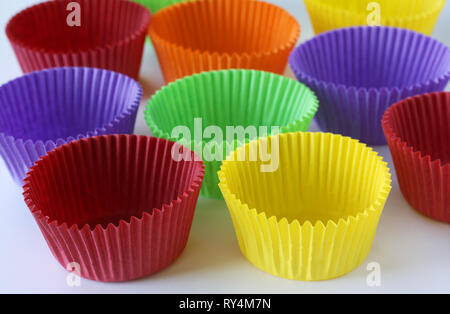 Colorata carta vuoto forme di capsule per muffin e tortine su sfondo bianco - cottura dessert - close up su sfondo bianco Foto Stock