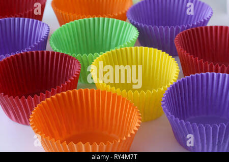 Molte colorate vuote forme di carta di capsule per muffin e tortine su sfondo bianco - cottura dessert - close up su sfondo bianco Foto Stock