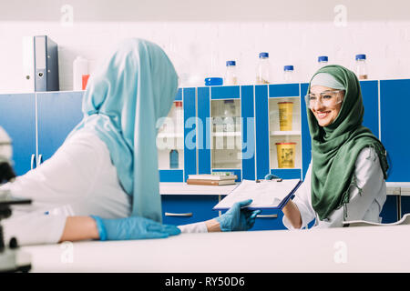 Femmina scienziati musulmani hijab come azienda appunti durante l'esperimento in laboratorio chimico Foto Stock