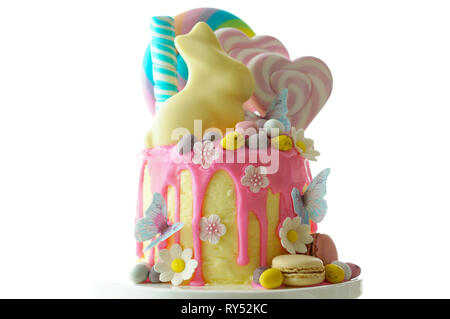 Sulla tendenza di Pasqua tema candy land gocciolare torta decorata con connettori lollipop, candy uova e cioccolato bianco bunny in parte messa in tavola. Foto Stock