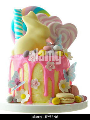 Sulla tendenza di Pasqua tema candy land gocciolare torta decorata con connettori lollipop, candy uova e cioccolato bianco bunny in parte messa in tavola. Foto Stock