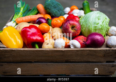 Frutta e verdura. Una cassa di legno d'annata piena di frutta fresca e verdure colorate per promuovere la vita sana a base di piante vegane. Foto Stock