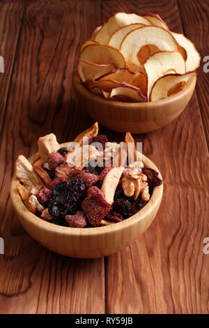 Mix di frutta secca pezzi di mela e pera, secche Prugne blu, fragole, lamponi e ciliegie e noci in una ciotola di bambù e i chip Apple in un Foto Stock