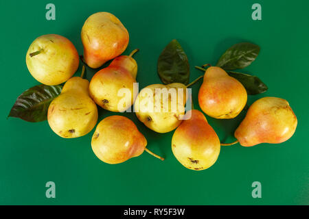 Pila di pere sparsi su sfondo verde Foto Stock