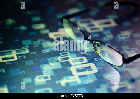 La lettura dei dati in età digitale. bicchieri e che scorre il codice binario di matrice. La profondità di campo di una immagine di bicchieri sul pannello di visualizzazione. di più linee di colore blu Foto Stock