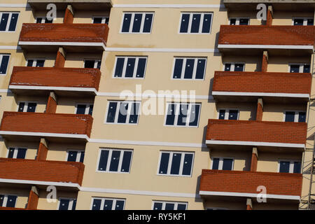 Parete di un alto edificio di mattoni casa, balconi rosso e pareti di colore giallo. Foto Stock