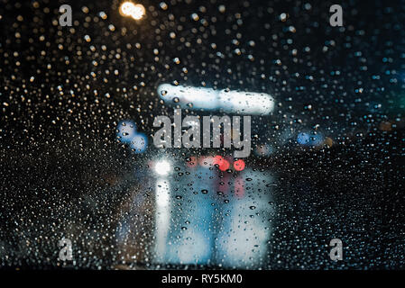 La vita reale delle gocce di pioggia scena ripresa dall'interno del parabrezza per auto luci di traffico di background Foto Stock