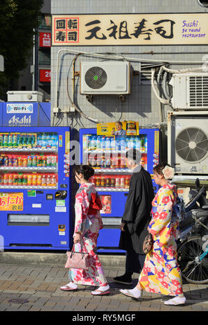 I giovani si cladded in kimono tradizionale passeggiando intorno ai negozi di Nakamise Dori nei quartieri del tempio senso-ji, Tokyo Asakusa JP Foto Stock