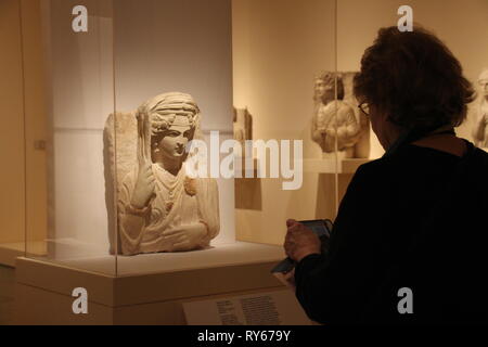 New York, Stati Uniti d'America. Undicesimo Mar, 2019. I visitatori a stare di fronte ad un antico busto in pietra di Bat'a, figlia di Moqim, (nipote di) Malku da Palmyra, che secondo le stime degli esperti, è stato creato nel tardo II o agli inizi del III secolo dopo Cristo. È di proprietà del Musee de Grenoble e può essere visto dal 18 marzo 2019 al Metropolitan Museum di New York nella mostra "Il mondo tra imperi". (Dpa show di New York sulla distruzione del patrimonio culturale nel vicino Oriente, 12.03.2019) Credito: Christina Horsten/dpa/Alamy Live News Foto Stock