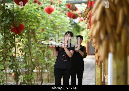 (190312) -- Pechino, 12 marzo 2019 (Xinhua) -- i membri dello staff servono piatti in un ristorante Longwangba villaggio di Xiji nella contea di Guyuan, a nord-ovest della Cina di Ningxia Hui Regione autonoma, il 30 agosto 2018. (Xinhua/Wang Peng) Foto Stock