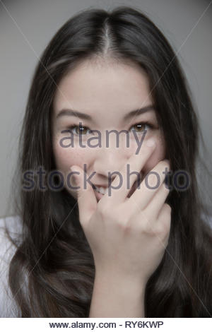 Ritratto bella bruna ragazza adolescente con occhi marroni di ridere con la mano sulla bocca