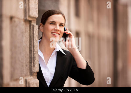 Imprenditrice sorge a fianco dell edificio a parlare su un telefono cellulare. Foto Stock