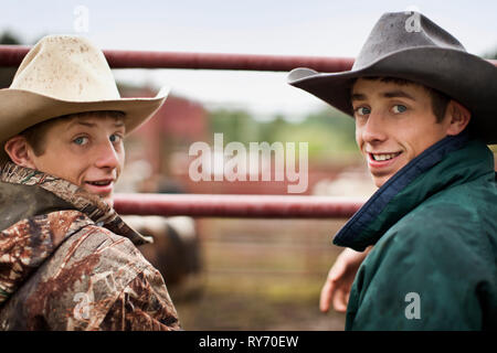 Ritratto di due cowboy teenage appoggiata sul cancello. Foto Stock