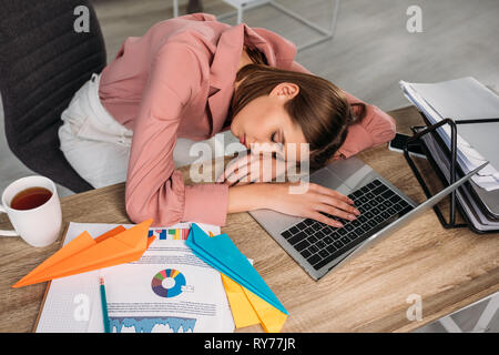 Vista aerea della donna attraente a dormire la scrivania vicino al portatile a casa Foto Stock