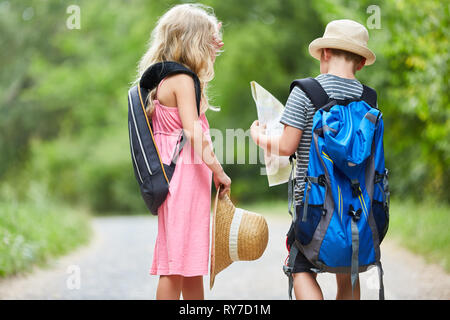 Due gemelli figli sulla natura escursione con la mappa e zaino Foto Stock